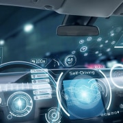Interior view of a self-driving car with a detailed ADAS interface on the windshield. The dashboard displays speed, navigation, and vehicle status, while the windshield projects interactive graphics for autonomous driving functions, such as adaptive cruise control and lane-keeping assistance.