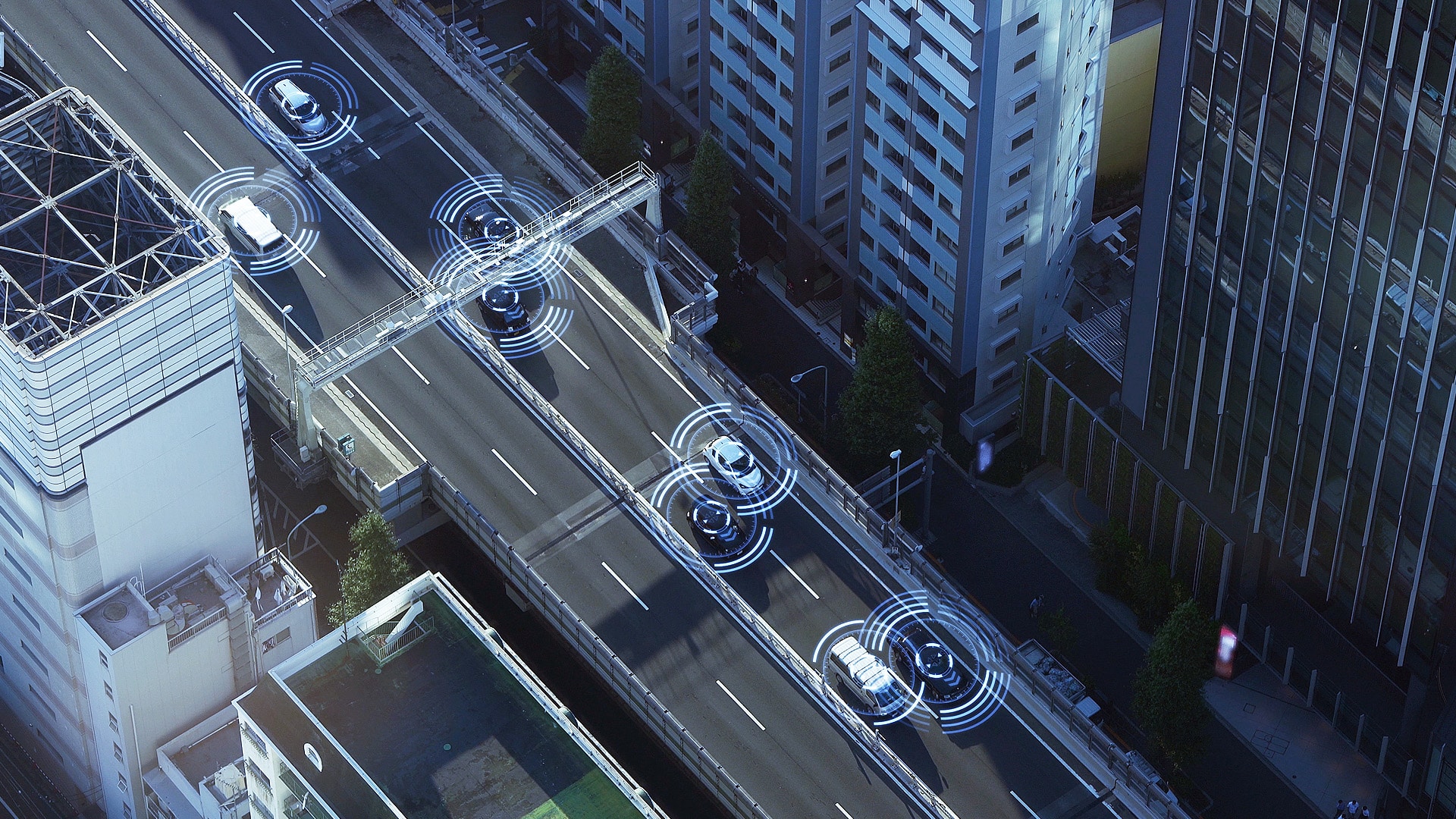 A top-down view of a city street at night with three vehicles, each highlighted by circular ADAS graphics representing sensors and connectivity. The advanced driver-assistance systems (ADAS) in these vehicles are actively scanning the environment for navigation and safety.